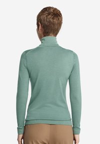 Jasnozielony sweter typu golf z dopasowanym krojem, długimi rękawami i ściągaczami, uszyty z miękkiego materiału. Gładka faktura z minimalną ilością szwów.