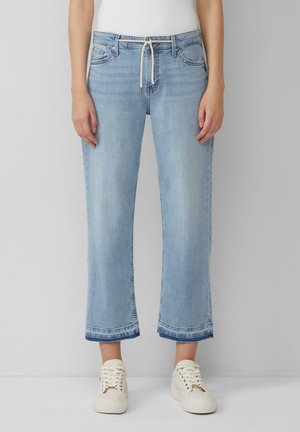Helle blaue Jeans im geraden Schnitt mit umgeschlagenen Säumen und einem Kordelzugbund; kombinieren Sie sie mit weißen Sneakers für einen lässigen Look.
