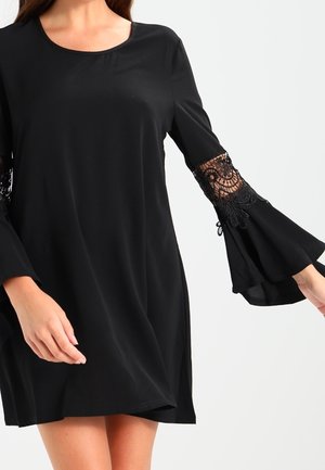 Schwarzes Kleid mit langen Glockenärmeln, die mit filigranen Spitzenmotiven verziert sind. Glatte Textur mit rundem Halsauschnitt und lockerer Passform.
