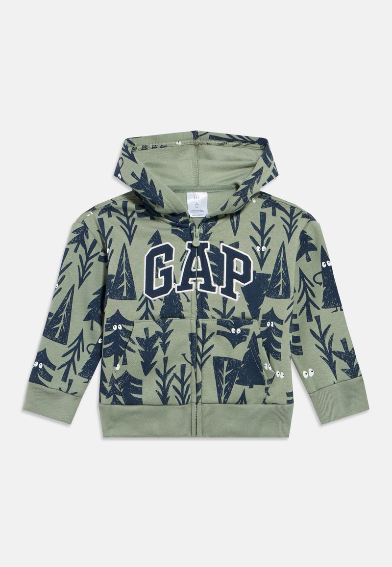 Gyermek zöld cipzáras kapucnis pulóvere tengerészkék fák, állatok és szemek mintával, valamint nagy fehér GAP logóval a mellkason.