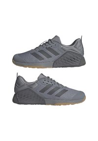 Baskets de sport grises avec une tige en maille respirante, une semelle en caoutchouc et une texture latérale distinctive. Elles présentent trois rayures noires et un laçage ajustable.