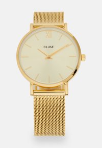 Montre en mailles dorées avec un cadran rond, un cadran jaune clair, le texte "CLUSE" en noir et des index horaires minimalistes. Dispose d'un boîtier et d'une couronne couleur or.