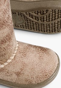 Stivale marrone con texture, punta arrotondata e cuciture visibili, con una tomaia decorata e suola in gomma con piccoli rilievi di presa.