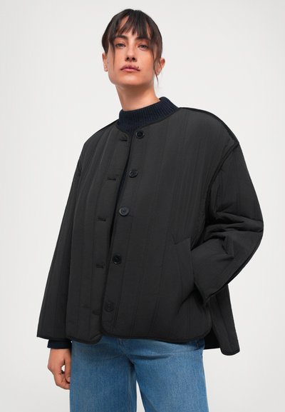 Schwarze gesteppte Jacke mit rundem Kragen, vorderem Knopfverschluss und seitlichen Taschen. Sie verfügt über vertikale Steppungen und eine lockere Passform.