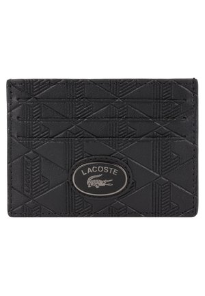 Porte-cartes en cuir noir avec un motif géométrique texturé, arborant un logo oval de Lacoste en relief et plusieurs emplacements pour cartes.