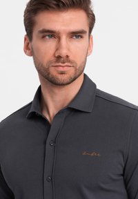 Grijze poloshirt van katoen, met een kraagdesign, knoopsluiting en een subtiele oranje geborduurde logo op de borst.