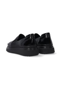 Černé lakované kožené slip-on boty s tlustými černými gumovými podešvemi, s hladkým povrchem a minimalistickým designem bez tkaniček.