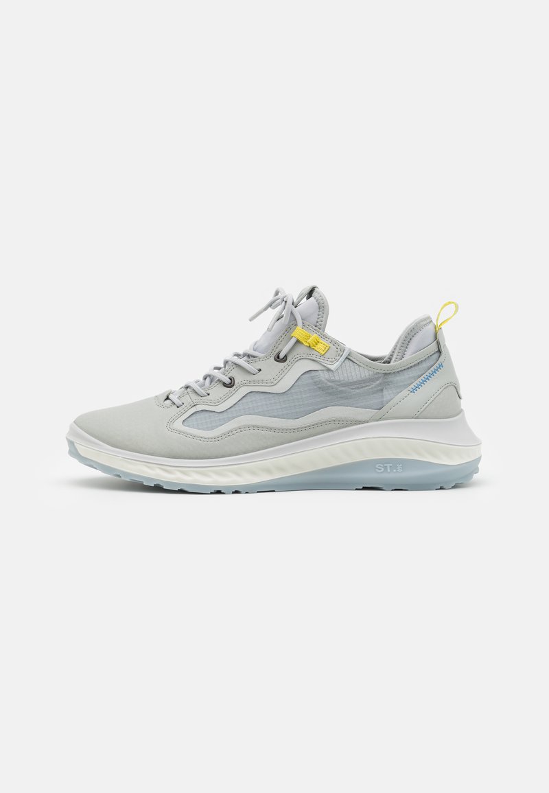Gray athletic shoe with mesh and suede material, prominent white sole, yellow accent, and lace-up design. Features textured overlays.