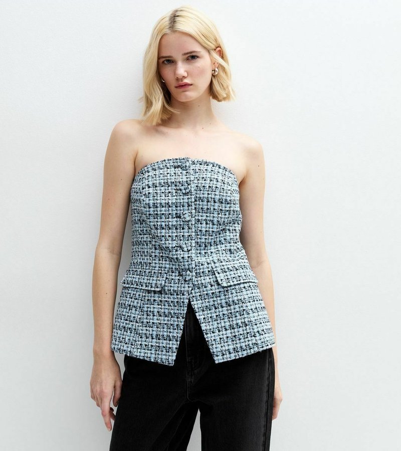 Top de tweed sin tirantes en un patrón de cuadros azul y blanco, con un diseño ajustado, dos bolsillos delanteros y una ligera forma de peplum.