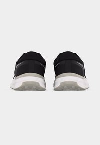 Ζευγάρι μαύρα και γκρι παπούτσια για τρέξιμο, εμφανιζόμενα από πίσω, με λευκές σόλες και υφασμένη επιφάνεια πέλματος, σε απλό γκρι φόντο.