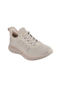 Lys beige idrettssko med et pustende meshupp og teksturerte sidepaneler, samt en tykk, rillede yttersåle. Har matchende snøring og merke.