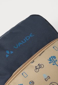 Navy blue bag with blue "VAUDE" logo, featuring a beige zippered pocket patterned with bicycles, trees, and icons. Textured fabric.