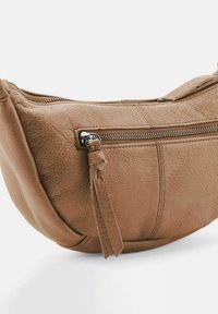 Bolso de cuero marrón con forma redondeada, superficie texturizada y un bolsillo exterior con cremallera y un tassel decorativo.