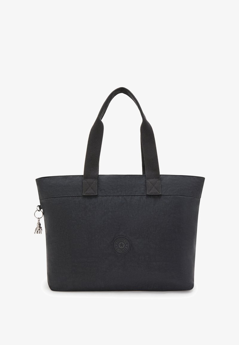 Sac fourre-tout noir en tissu texturé, avec deux poignées et un logo rond. Présente un petit charm accroché sur un côté. Forme rectangulaire simple.