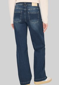 Pantalones vaqueros de mezclilla azul oscuro con un diseño de pierna recta, que cuentan con dos bolsillos traseros y una pequeña etiqueta de la marca en la cintura.