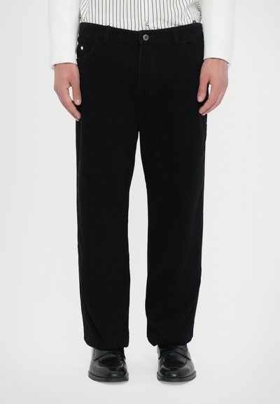 Pantaloni in corduroy neri con design a gamba dritta, dotati di tasche frontali, chiusura con bottone e una texture liscia. Abbinati a scarpe nere.