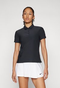 Black polo shirt with a classic collar, five button placket, short sleeves, and a lightweight, smooth texture. White logo accent on sleeve.