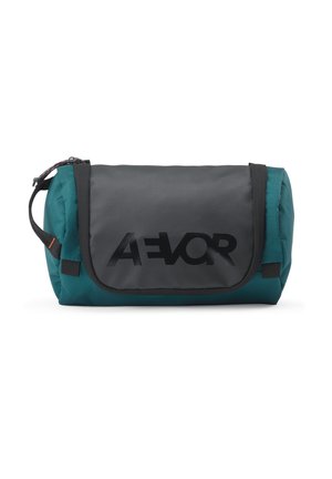 Kompakte türkise und schwarze Kulturtasche mit einer vorderen Klappe, die ein auffälliges schwarzes Logo zeigt, und einem seitlichen Tragegriff.