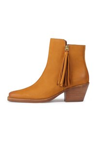 Tan-nahkasa ankle boot, jolla on terävä kärki, sivuvetoketju ja koristeelliset tupsut. Varustettu pinoitulla korolla ja sileällä pinnalla.