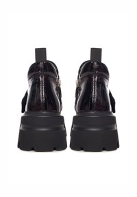 Chaussures en cuir verni noir avec une semelle chunky noire, dotées d'une fermeture éclair et d'un panneau texturé sur les côtés.