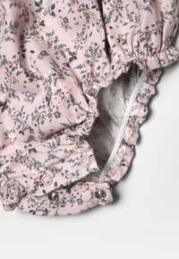 Oltre a un grazioso motivo floreale rosa, questo completino per neonati presenta bottoni a pressione all'inguine e rifiniture arricciate elastiche sulle maniche e sulle aperture delle gambe.