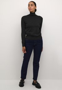 Tumehall turtleneck-sviiter, keha ligi rippuv, pika varruga. Kombineeritud siniste teksapükstega ja mustade lohvkatega, millel on kuldsed aksessuaarid.
