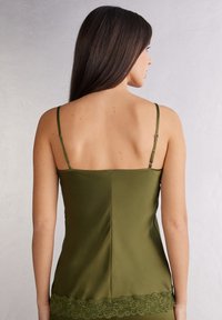 Oliwkowy satynowy top na ramiączkach z regulowanymi cienkimi paskami i koronkowym wykończeniem na dole, charakteryzujący się gładką, elegancką fakturą.