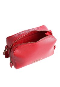 Röd läderhandväska med en texturerad yta, dubbla dragkedjor och en logotypaccent på framsidan. Har en rymlig, öppen insida.