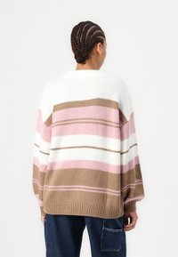 Knit sweater in beige, pink, and white stripes. Oversized design with dropped shoulders and a ribbed hem. Soft texture and casual fit.