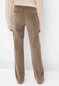 Bruine corduroy broek met een relaxed fit, voorzien van een elastische tailleband en twee achterzakken. Het materiaal heeft een zachte, gestructureerde afwerking.