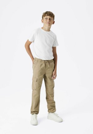 Beige Cargo-Hosen mit elastischem Bund und mehreren Taschen, kombiniert mit einem schlichten weißen T-Shirt und weißen Sneakers. Schlichtes, lässiges Design.