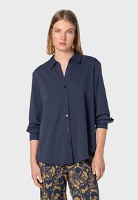 Camicia button-up blu navy in un tessuto morbido con colletto classico e maniche arrotolate, dotata di bottoni coordinati e una vestibilità comoda.