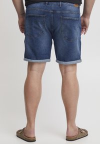 Jeansshorts med mörk tvätt, med uppvikt fåll och femficksdesign. Bak på shortsen finns två påsydda fickor och en läderetikett.