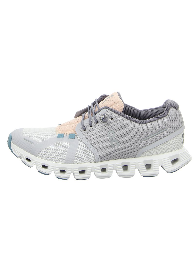 Zapatilla deportiva de color gris claro con parte superior de tejido de malla, acentos en rosa suave y suela blanca acolchada con cortes alargados para transpirabilidad.