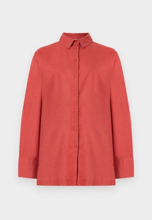 Chemise boutonnée à manches longues de couleur orange rouille avec un col pointu et des poignets, présentée sur un fond blanc uni.