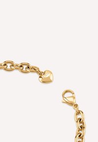 Bracciale in catena dorata con grandi maglie, dotato di un ciondolo a forma di cuore impresso con "GUESS" e chiusura a moschettone.