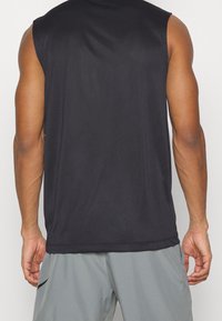 Czarny bezrękawnik sportowy wykonany z gładkiego materiału, o swobodnym kroju i zaokrąglonym dolnym wykończeniu. Widoczne szwy, bez graficznych wzorów.