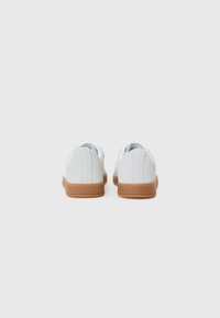 White leather shoes with a rubber gum sole. Features a smooth finish and rounded heel design. No visible patterns or accents.
