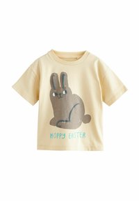 Krämfärgad bomull T-shirt med en grafik av en sittande brun kanin och texten "HOPPY EASTER" i turkos nedanför. Kort ärm.