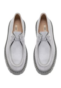 Chaussures en daim gris de forme arrondie, avec un bord cousu et une semelle en caoutchouc gris. Des lacets passés à travers de petites œillets mettent en valeur le design.