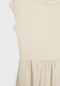 Cream-colored ribbed dress with short sleeves, fitted bodice, and gathered skirt. Smooth fabric texture with a soft appearance.