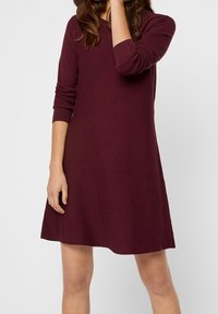 Burgunderfarbenes Strickkleid mit langen Ärmeln, einem runden Ausschnitt und einem leicht ausgestellten Saum. Hergestellt aus einem weichen, strukturierten Stoff.