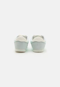 Sneakers azzurri chiari con una finitura liscia e texturizzata, dotati di un tacchetto bianco e di un colletto imbottito per comfort e supporto.