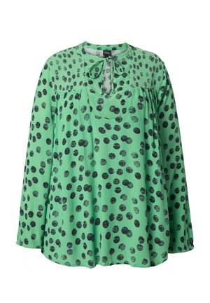 Groene blouse met zwarte stippen, lichtgewicht stof, losse pasvorm, ronde halslijn met strikdetail en lange mouwen. Geplooid ontwerp aan de voorkant.