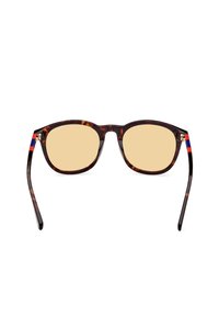 Gafas de sol de carey con lentes amarillos, parte superior plana y montura ancha. Acentos en azul y rojo en las patillas. Forma rectangular clásica.