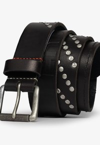 Czarny skórzany pasek z chwościkami w kolorze srebrnym i czerwonym przeszyciem, z matową metalową klamrą. Warstwy tworzą teksturowy efekt wizualny.