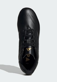 Zapatilla deportiva de cuero negro con superficie texturizada, cordones planos y detalles dorados en la lengüeta. Presenta un diseño aerodinámico para el rendimiento.