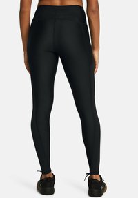 Leggings negros con una cintura alta, hechos de una tela suave y elástica. Presentan costuras planas y un corte ajustado. Combinados con zapatillas deportivas negras.