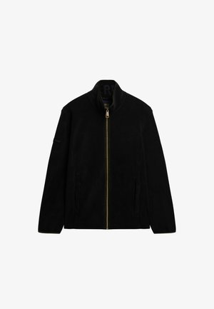 Veste noire zippée en tissu doux. Dotée d'un col montant, de deux poches latérales et d'un logo discret sur la manche. La fermeture éclair est de couleur dorée.