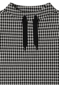 Materiał w czarno-białą kratkę o wysokim dekolcie i dwóch czarnych sznurkach przy kołnierzy, z teksturowanym splotem.